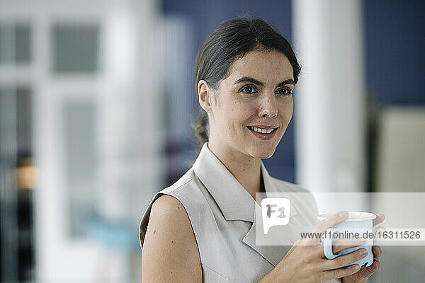 Businesswoman taking coffee break while standing at office