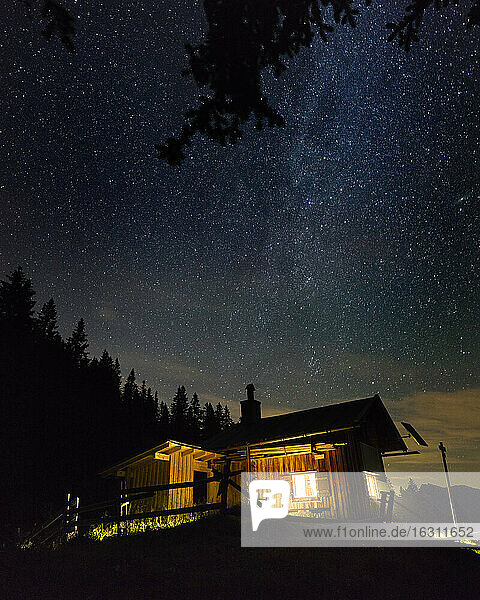 Starry night sky over secluded mountain hut