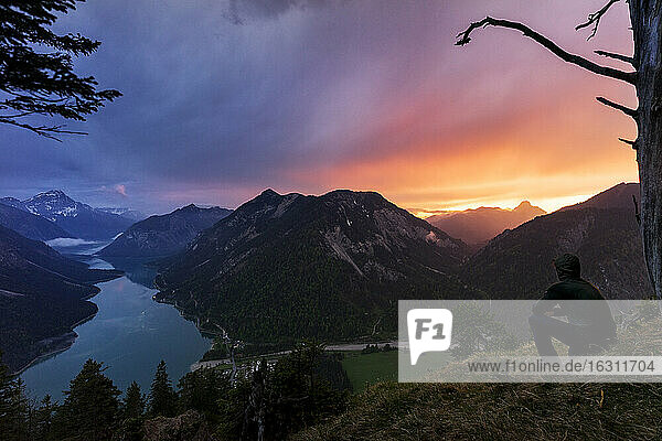 Österreich  Tirol  Silhouette eines Mannes  der den Plansee und die umliegenden Berge bei Sonnenuntergang bewundert