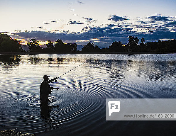 USA  Utah  Salem  Silhouette of man fly fishing in lake at dusk