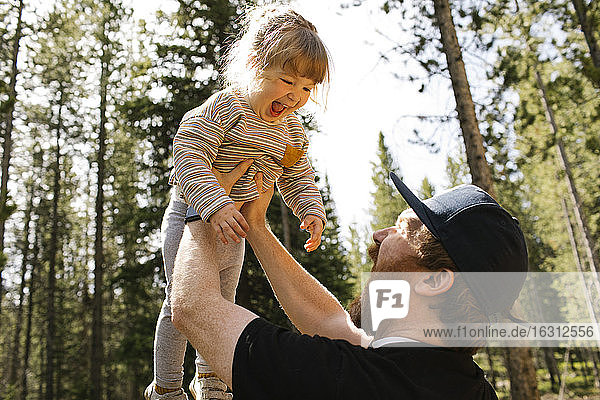 Father holding smiling daughter (2-3) in forest  Wasatch-Cache National Forest