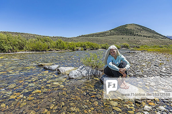 USA  Idaho  Sun Valley  Woman sitting on rock in river