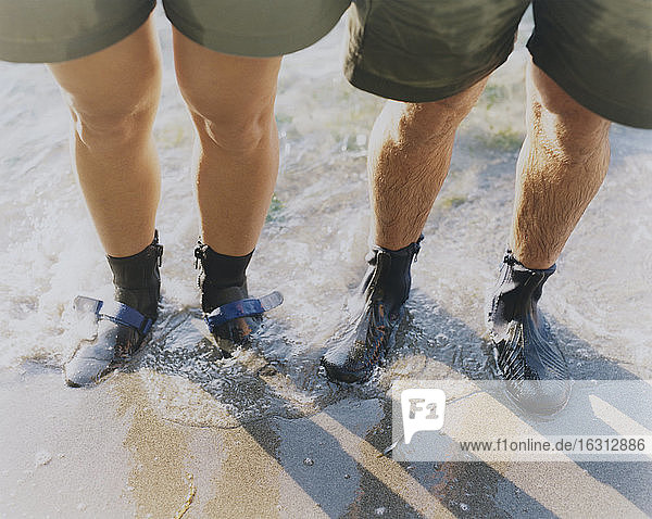 Man and woman wearing waterproof booties  standing in surf