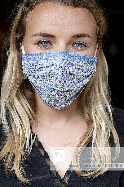 Bildnis einer jungen blonden Frau mit blauer Gesichtsmaske.