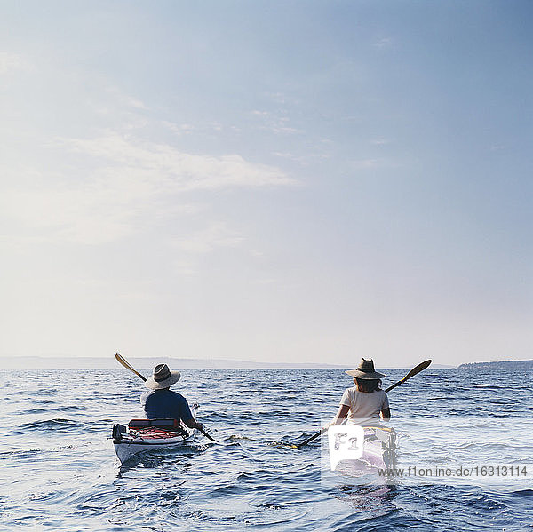 Mann und Frau mittleren Alters beim Seekajakfahren auf ruhigen Gewässern