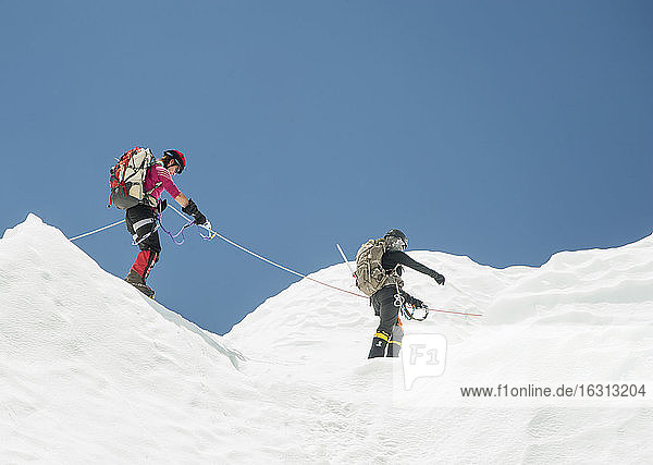 Zwei Bergsteiger im Schnee auf einem Berg  zusammen angeseilt.