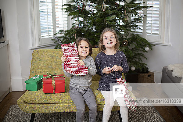 Zwei junge Mädchen sitzen in rot-weißen Weihnachtsstrümpfen und lächeln in die Kamera.
