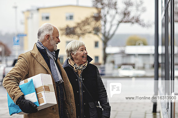 Lächelndes älteres Paar mit Paket im Winter in der Stadt