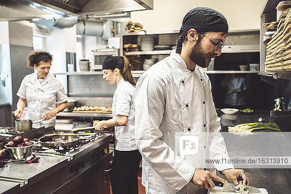 Männlicher Chefkoch schneidet Pilze in Großküche