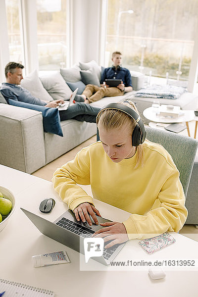 Hochwinkelansicht eines Mädchens mit Laptop am Tisch zu Hause