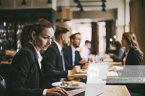 Seitenansicht einer Geschäftsfrau mit Laptop im Restaurant