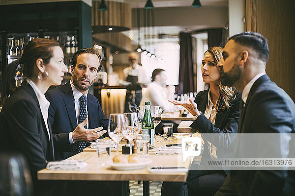 Männliche und weibliche Berufstätige beim Geschäftsessen im Restaurant im Gespräch