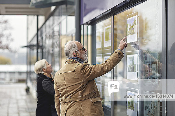 Älterer Mann zeigt im Winter auf Glasfenster von Partnerin in der Stadt
