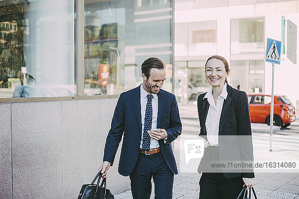 Happy male and female professionals in city