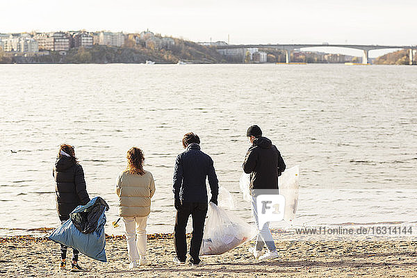 Rückansicht von Umweltschützern mit Mikroplastikmüll  die gegen den See laufen