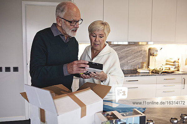 Älteres Ehepaar packt Paket über Kücheninsel zu Hause aus