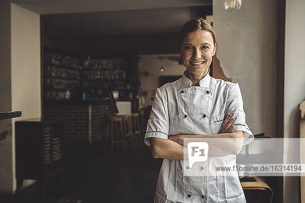 Portrait of smiling chef with arms crossed in restaurant