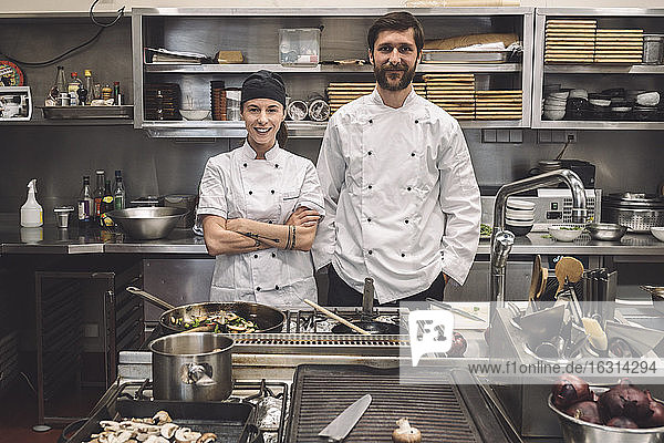 Portrait of smiling male and female chefs in commercial kitchen