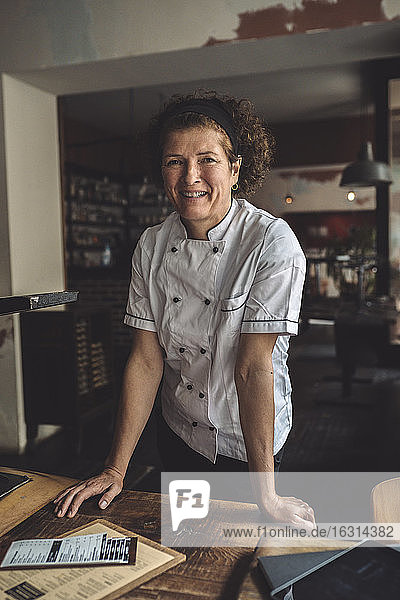 Porträt eines lächelnden reifen Kochs im Restaurant stehend