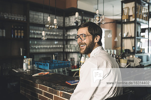 Side view of happy chef sitting in restaurant