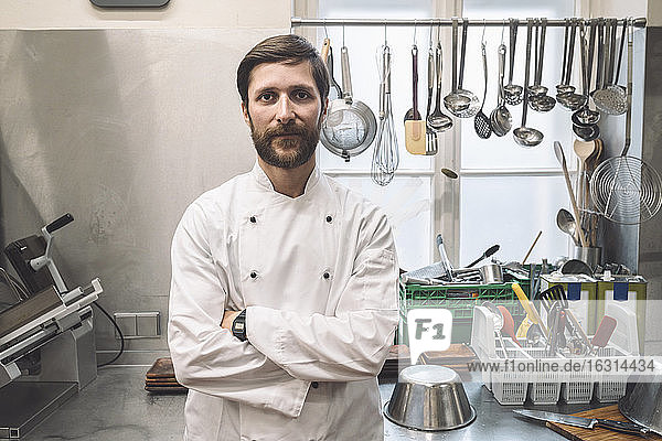 Portrait of confident chef with arms crossed standing in commercial kitchen