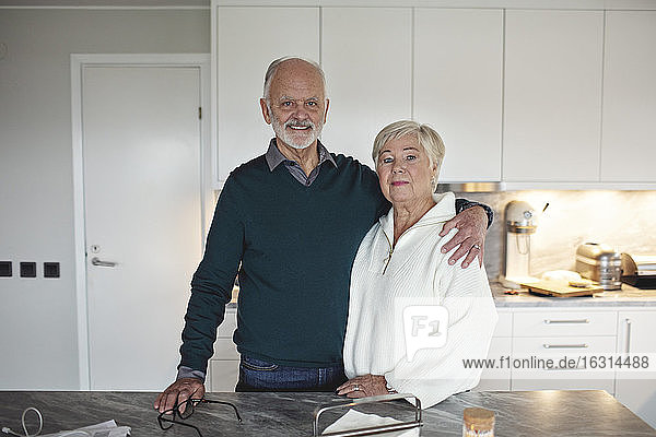 Porträt eines älteren Ehepaares  das zu Hause an der Kücheninsel steht