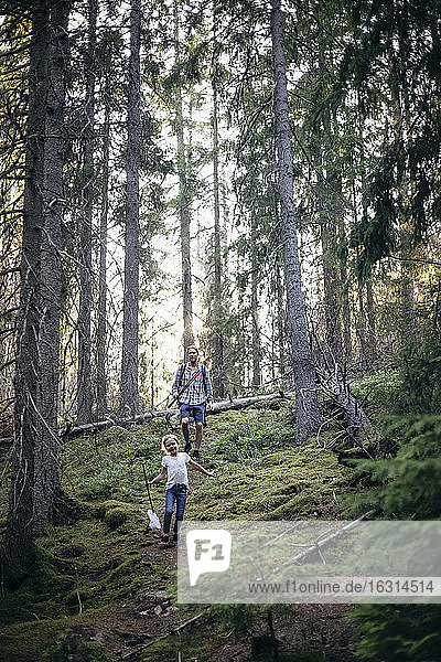 Smiling daughter and father walking in forest