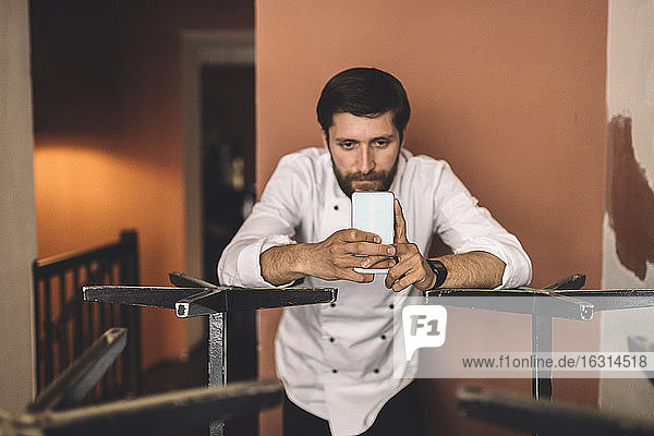Male chef using smart phone in restaurant