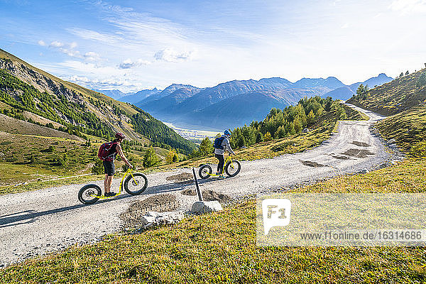 Zwei Personen haben Spass an der Trottinettabfahrt von der Bergstation Marguns nach Celerina  Engadin  Kanton Graubünden  Schweiz  Europa
