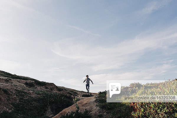 Boy running on beach hill  Peniche  Portugal