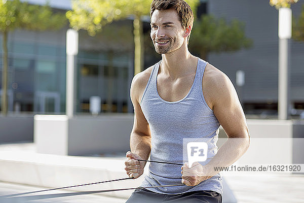 Porträt eines lächelnden Mannes  der mit einem Fitnessband trainiert