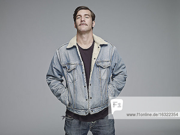 Porträt eines Mannes mit Jeansjacke vor einem grauen Hintergrund