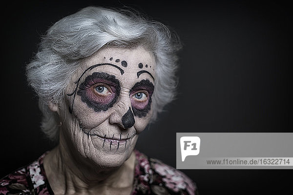Porträt einer älteren Frau mit Zuckerschädel-Make-up vor einem schwarzen Hintergrund