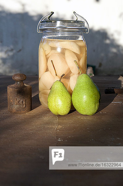 Preserving jar of sliced pears,  two fresh pears and old weight