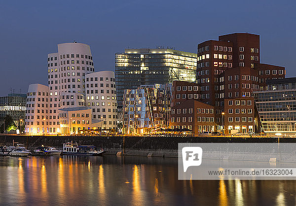 Deutschland  Düsseldorf  beleuchtete Gehry-Gebäude mit Medienhafen am Abend