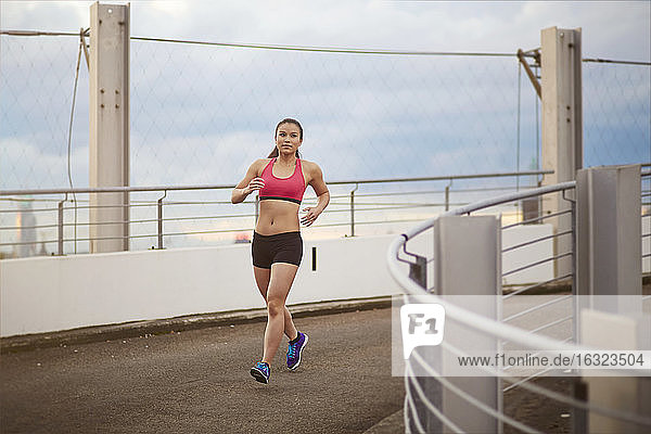 Young female Asian sportswoman jogging