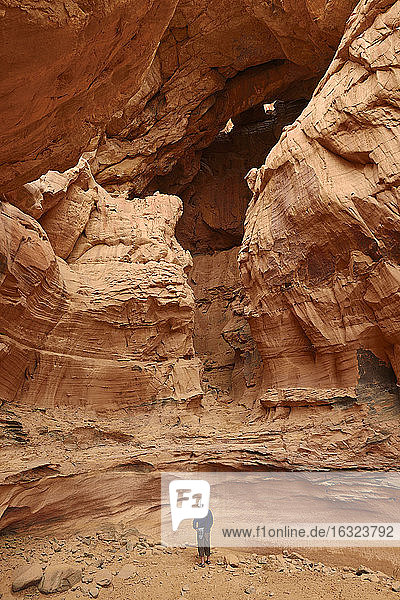 Algerien  Sahara  Tassili N'Ajjer National Park  Tadrart Region  Tisseteka  Mann steht in einem riesigen Schlagloch