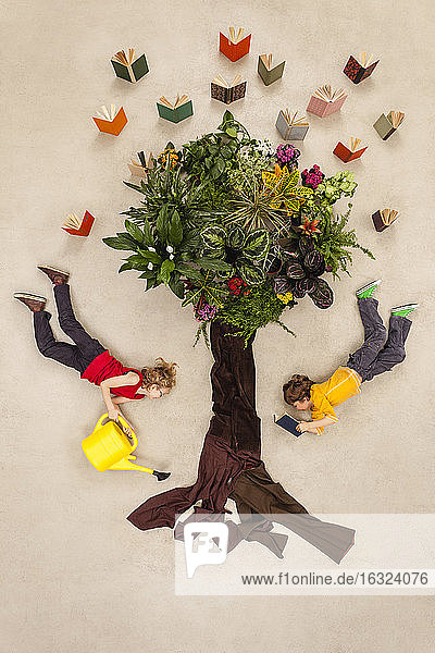 Boy and girl watering book tree