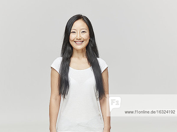 Porträt einer lächelnden Frau mit langen schwarzen Haaren und weißem Hemd