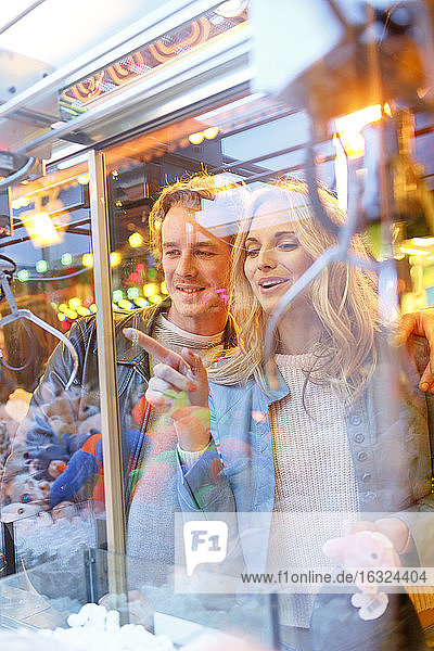 Junges Paar auf dem Jahrmarkt betrachtet die Preise im Fenster