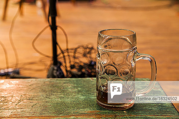 Deutschland  München  Oktoberfest  Bierkrug auf Holztisch  Bühnenausstattung im Hintergrund
