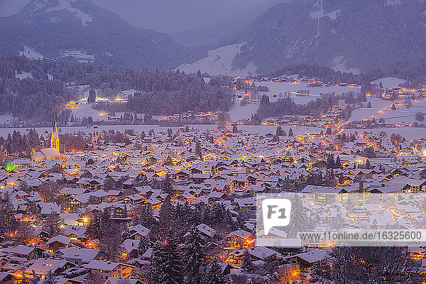 Deutschland  Bayern  Blick auf das schneebedeckte  beleuchtete Oberstdorf in der Dämmerung vor den Allgäuer Alpen