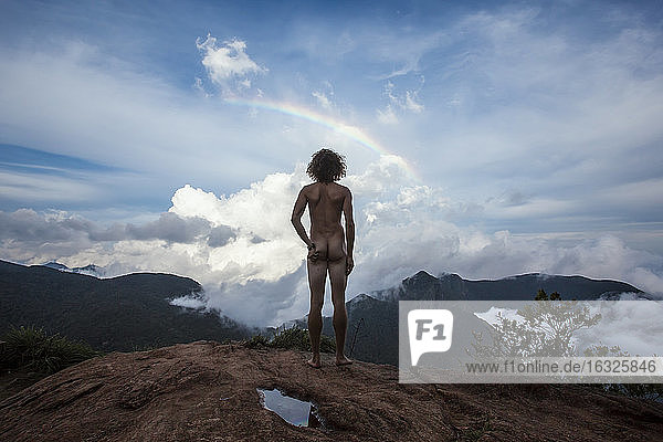 Sri Lanka  Horton Plains National Park  Rear view of nude man standing on viewing point  rainbow