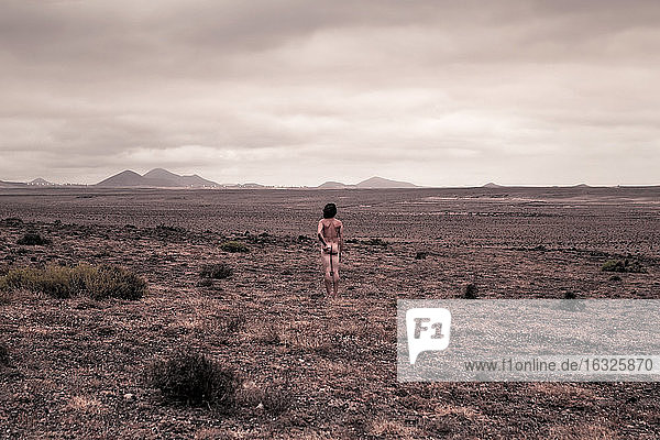 Lanzarote  Caleta de Famara  Rückansicht eines nackten Mannes in trostloser Landschaft