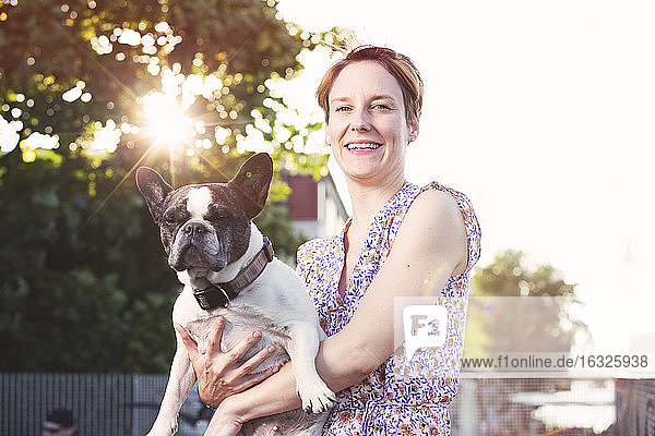 Porträt einer lächelnden Frau mit französischer Bulldogge