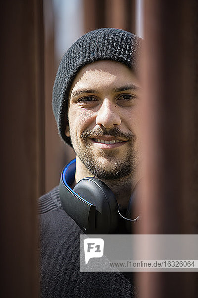 Portrait of smiling young man with headphones wearing wool cap