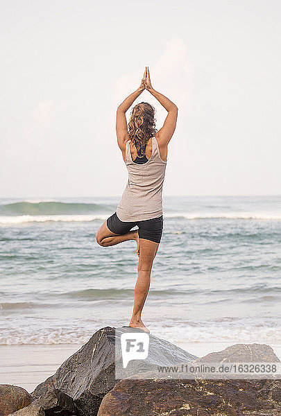 Sri Lanka  Kabalana  junge Frau übt Yoga an der Küste