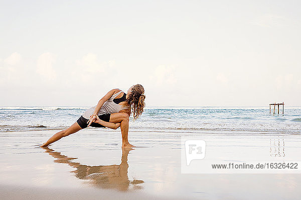 Sri Lanka  Kabalana  junge Frau übt Yoga am Strand