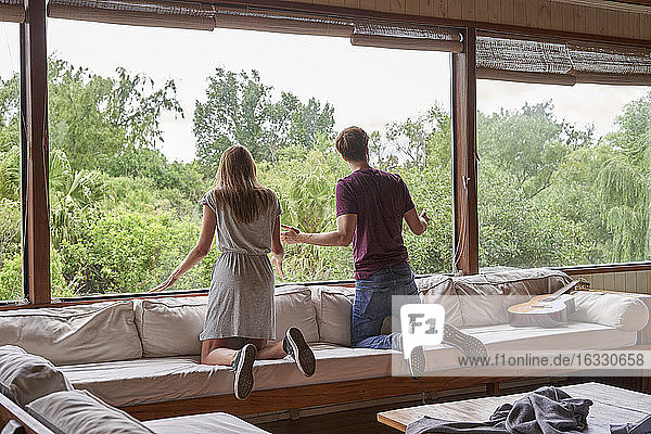 Junges Paar schaut durch ein Fenster hinaus