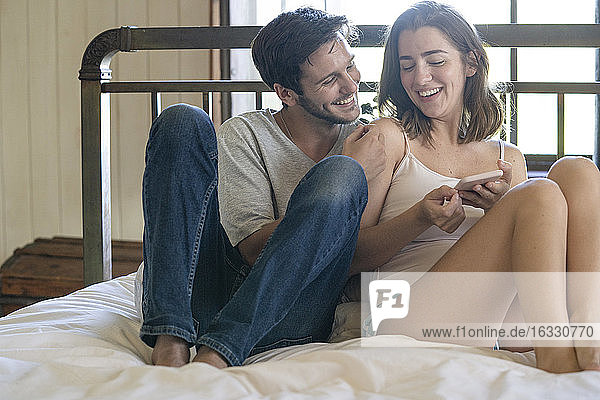 Junges Paar benutzt Smartphone im Schlafzimmer